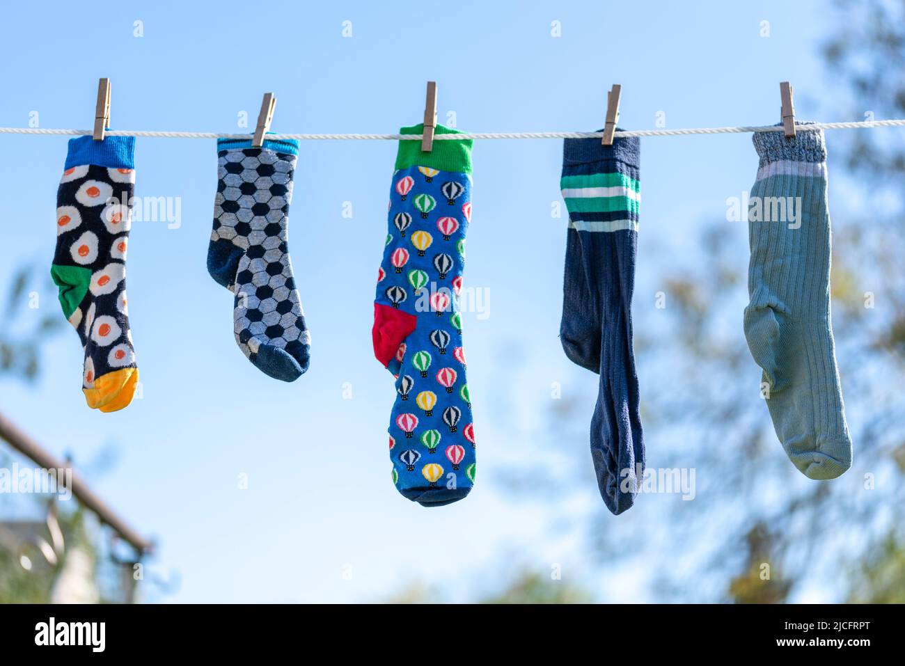 Chaussettes seules différentes sans partenaire sur une corde à linge, image symbole 'Lost Socks Memorial Day'. Banque D'Images