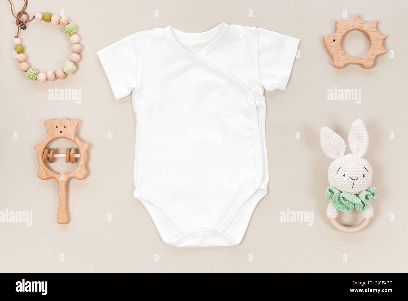 Cache-couche avec body blanc sur fond doux brun pastel. Accessoires pour enfants hochets en bois et jouets tricotés pour mockup avec des enfants en bas âge Banque D'Images