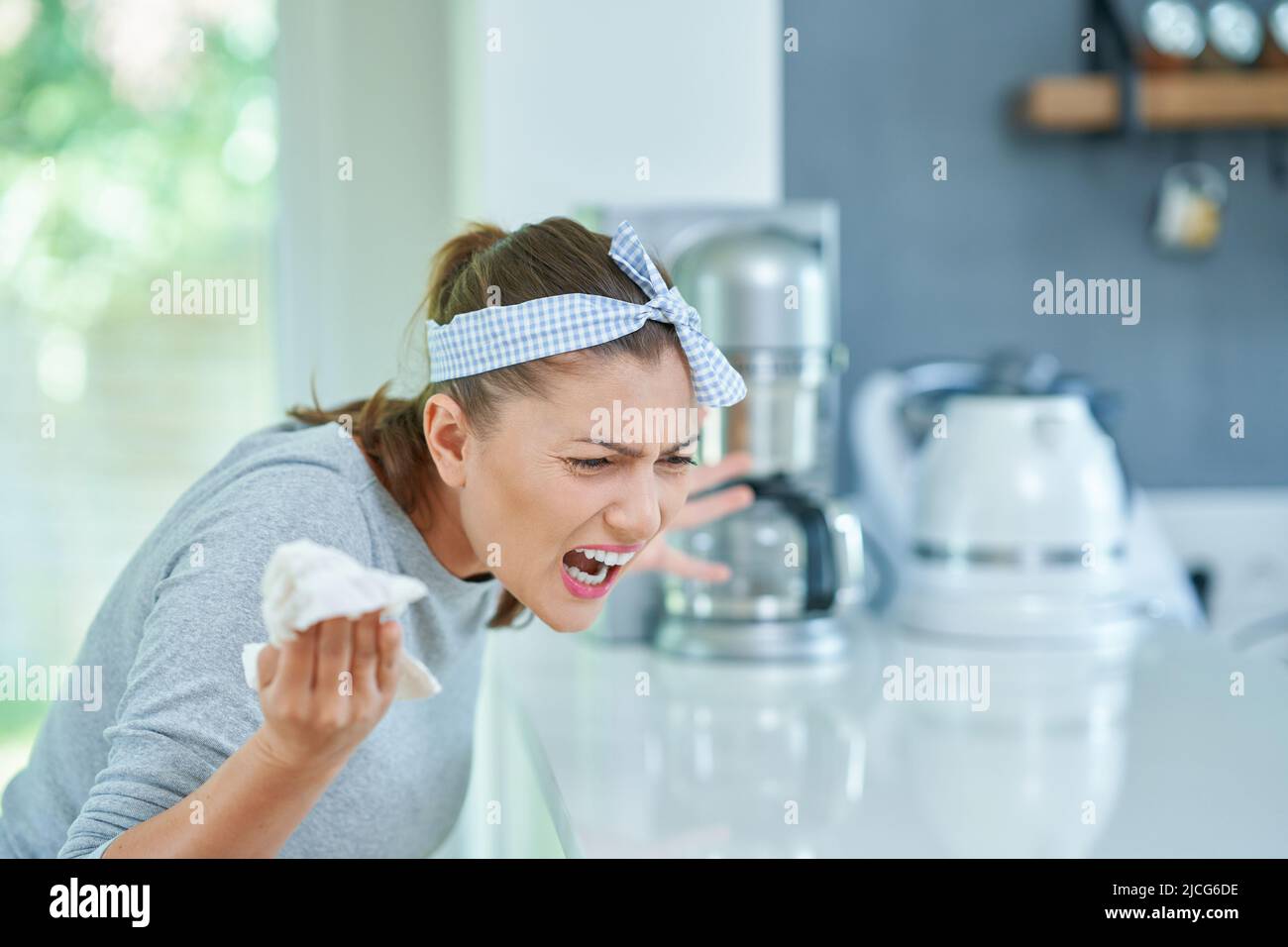 Jeune femme en colère dans la cuisine de nettoyage Banque D'Images