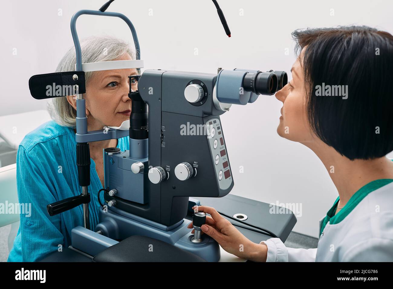 Optométriste féminin effectuant un test de vue auprès d'une femme âgée à la clinique moderne d'ophtalmologie. Examen oculaire et diagnostic de la vision Banque D'Images