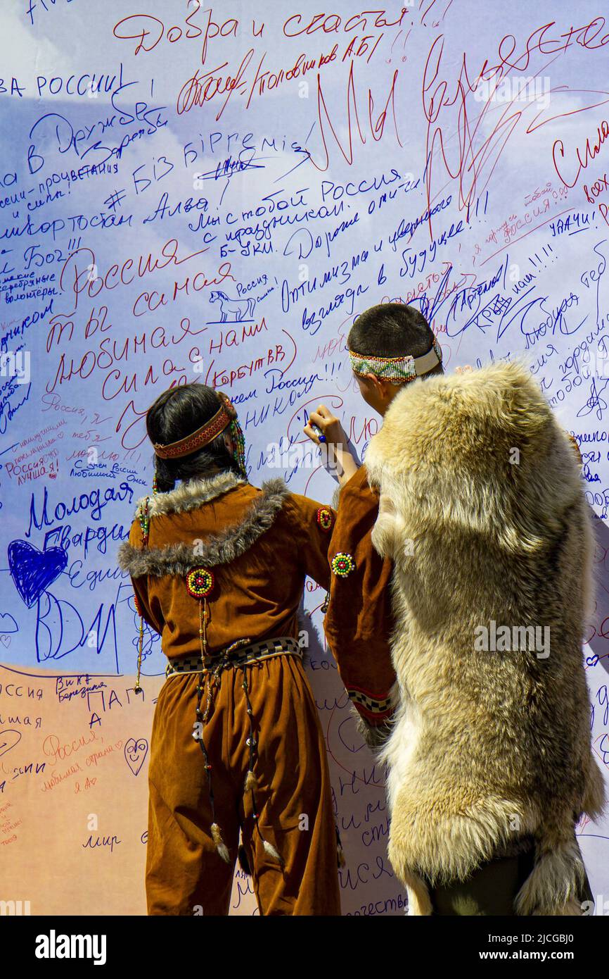 Omsk, Russie. 12 juin 2022. Fête de la Russie. Un gars avec une fille d'une équipe de danse ethnique de Yakutia écrire des souhaits au pays sur le mur des désirs Banque D'Images