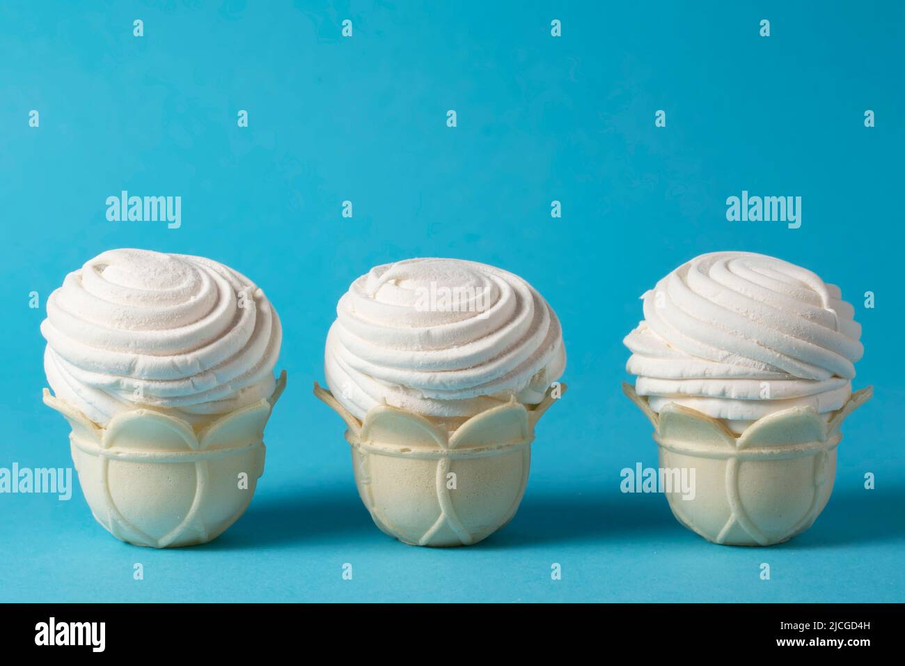 Trois superbes gâteaux blancs aérés sur fond bleu. Aliments sucrés à base de protéines et de sucre. Banque D'Images