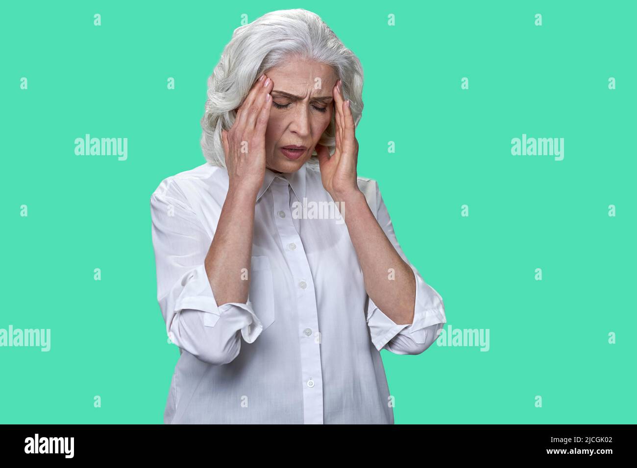 Femme d'affaires mature souffrant de migraine sur fond de couleur. Grand-mère ayant de forts maux de tête. Banque D'Images