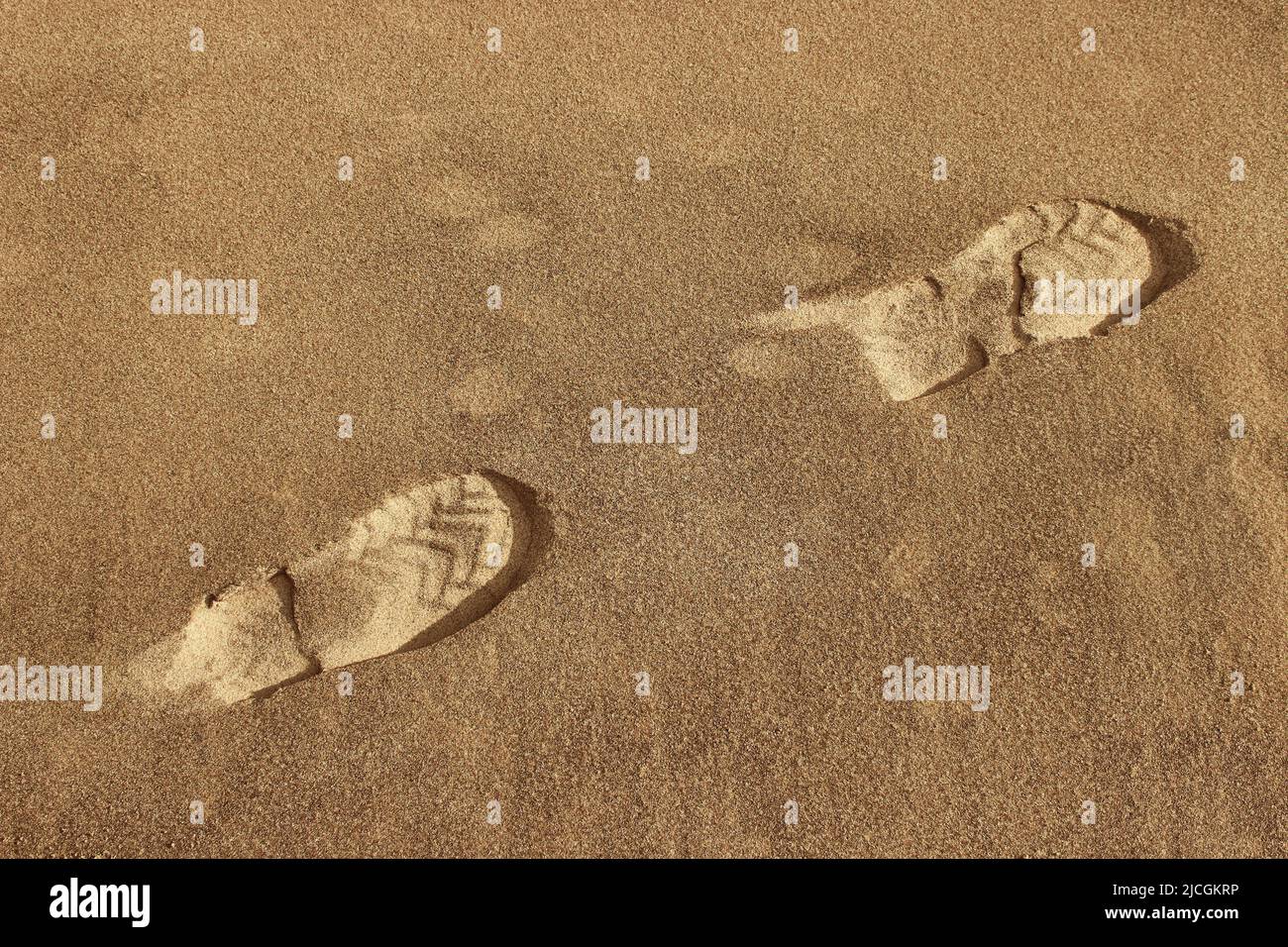 Traces de chaussures dans le sable. Empreintes de pas dans le sol sablonneux. Banque D'Images
