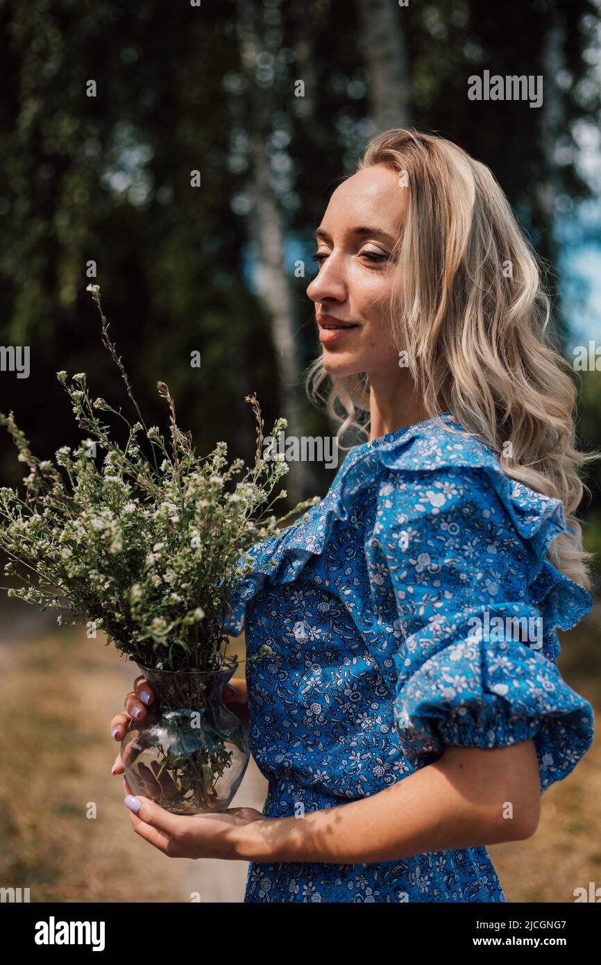 Une jeune fille en robe bleue tient des fleurs sauvages dans ses mains Banque D'Images