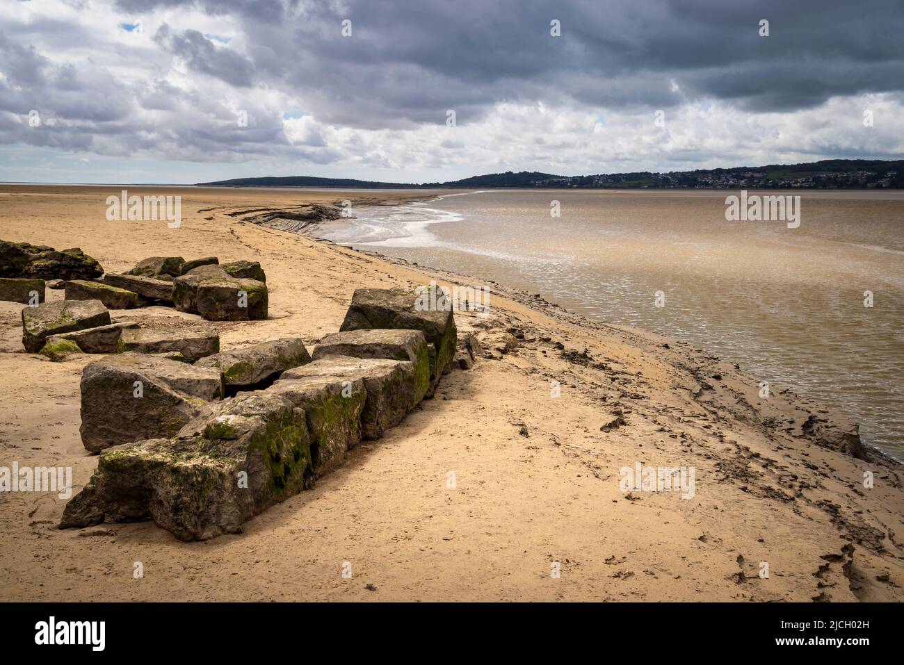 Roche calcaire et sable le long du chenal Kent qui coule dans la baie de Morecombe à marée basse avec Grange-over-Sands en arrière-plan, Lancashire, Angleterre Banque D'Images