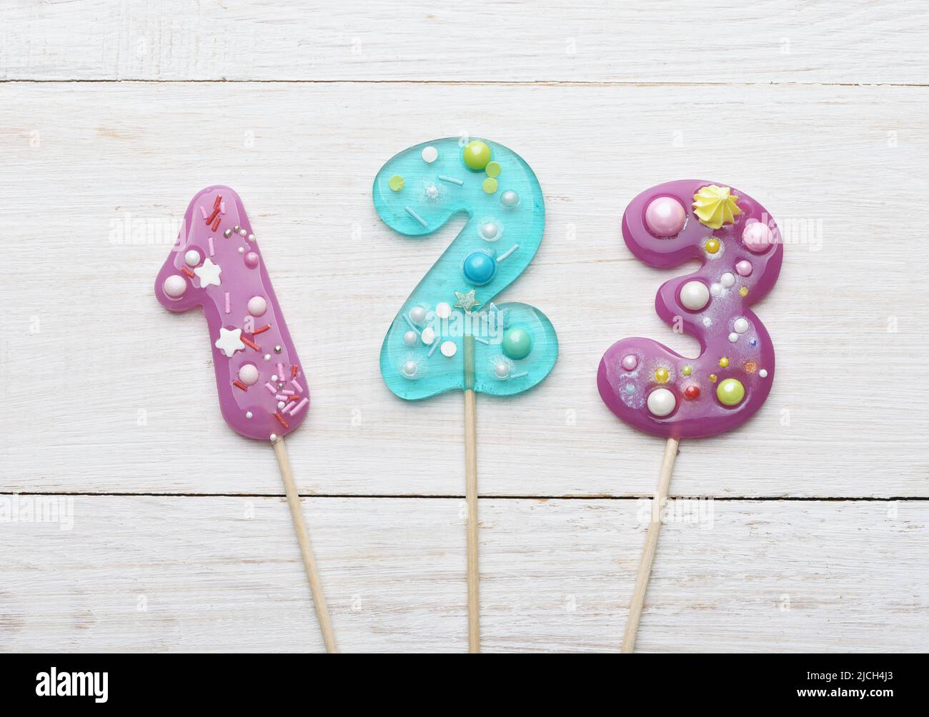 Vue de dessus de 1 2 3 numéros colorés sucettes sur fond blanc en bois Banque D'Images