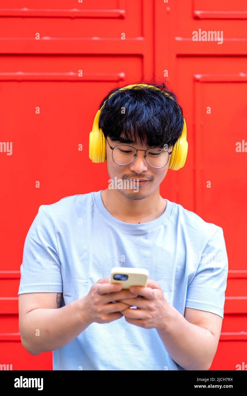 homme asiatique utilisant son smartphone pour écouter de la musique Banque D'Images
