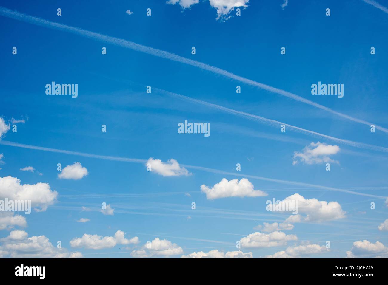 contrailles dans le ciel bleu nuageux Banque D'Images