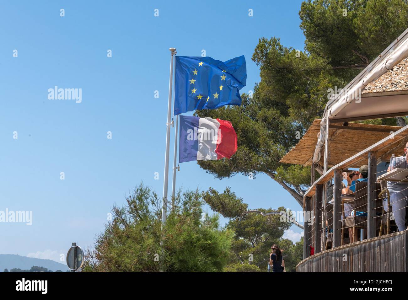 Le tricolore français et le drapeau de l'UE à côté d'un café en bord de mer sur la plage de Gigaro, Var, Provence-Alpes-Côte d'Azur, France. Banque D'Images