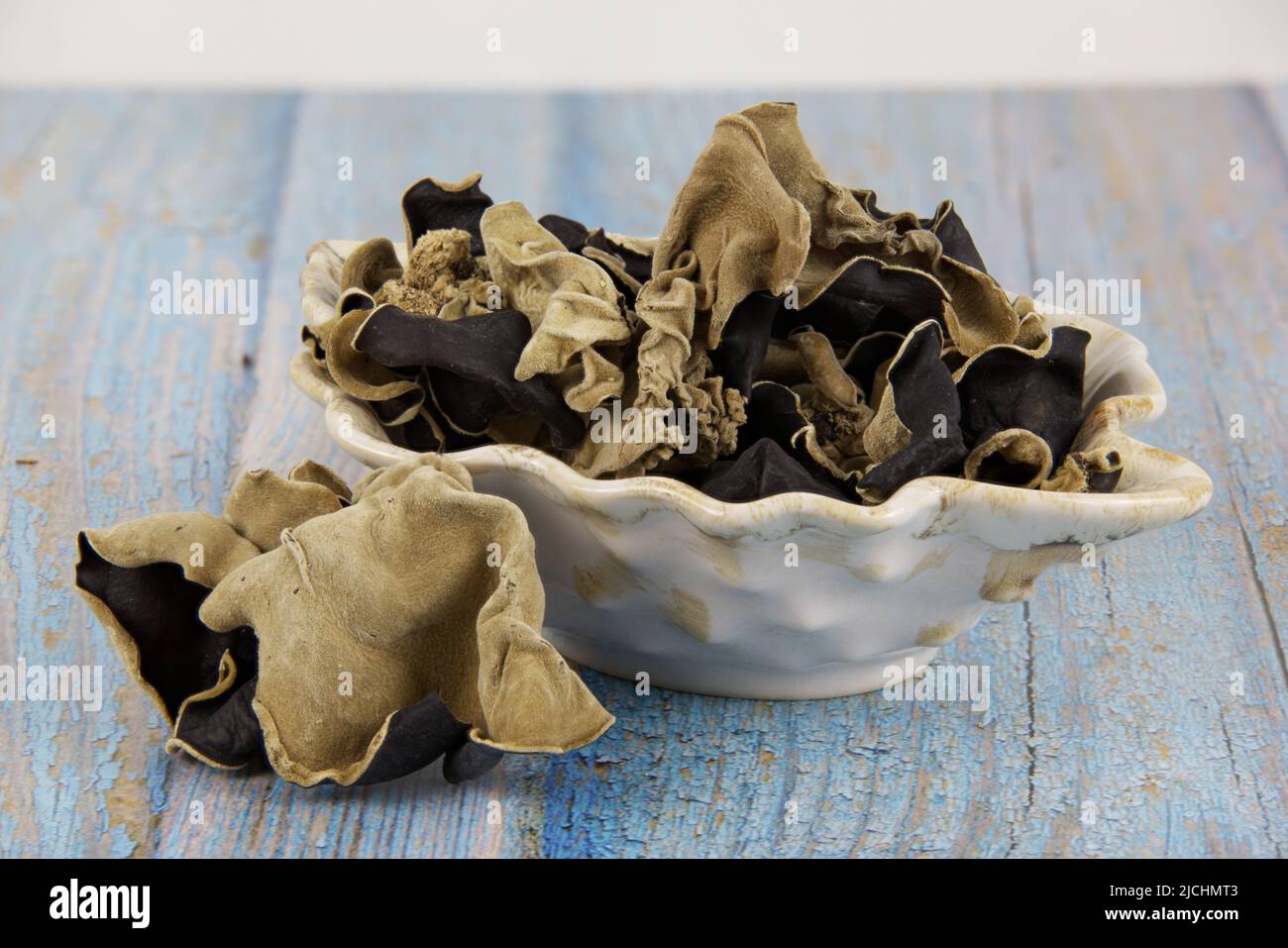 Champignons séchés connus sous le nom de champignon de l'oreille ou de l'oreille de juif, dans un plat en céramique, sur une ancienne table en bois, populaire dans la cuisine asiatique Banque D'Images