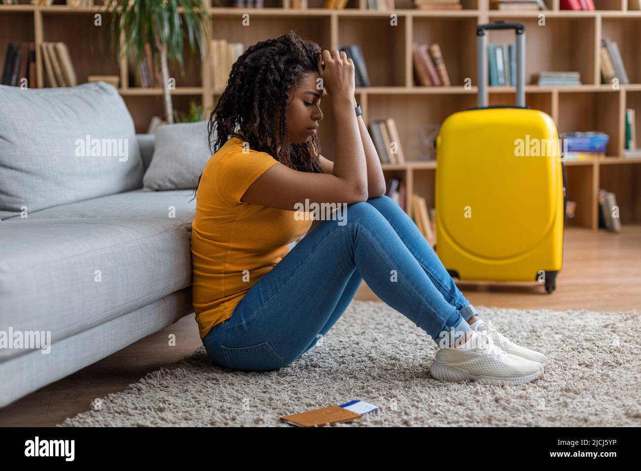 Oh non, le vol est annulé. Triste femme noire assise à la maison avec une valise emballée, touchant la tête et pleurant, espace de copie Banque D'Images