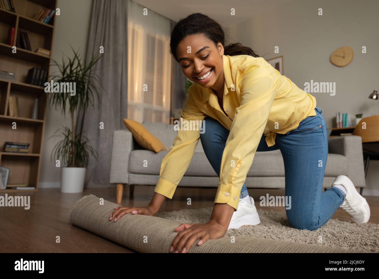 Une femme africaine couvre le sol avec moquette dans la salle de séjour à l'intérieur Banque D'Images