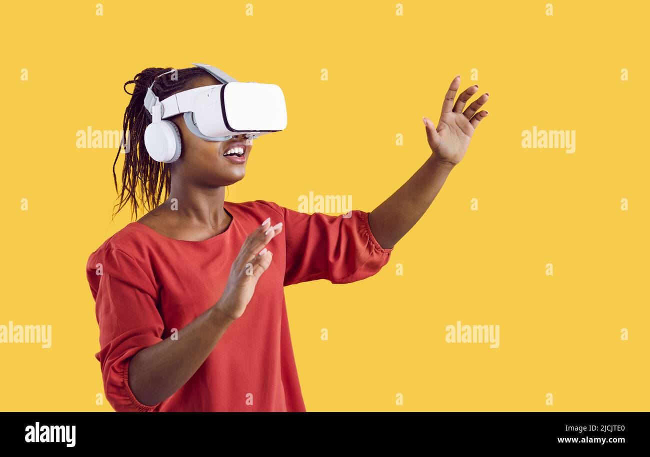 Bonne femme afro-américaine dans un micro-casque VR innovant qui fait l'expérience de la réalité virtuelle Banque D'Images