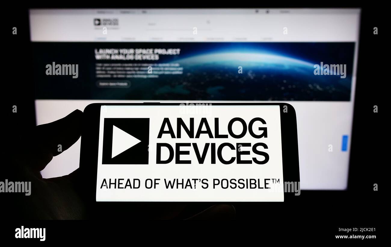 Personne tenant un téléphone portable avec le logo de la société de semi-conducteurs Analog Devices Inc. (ADI) à l'écran devant la page Web. Mise au point sur l'affichage du téléphone. Banque D'Images