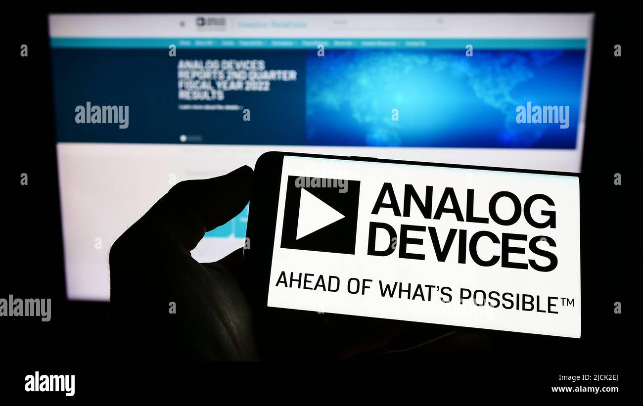 Personne tenant un smartphone avec le logo de la société de semi-conducteurs Analog Devices Inc. (ADI) à l'écran devant le site Web. Mise au point sur l'affichage du téléphone. Banque D'Images