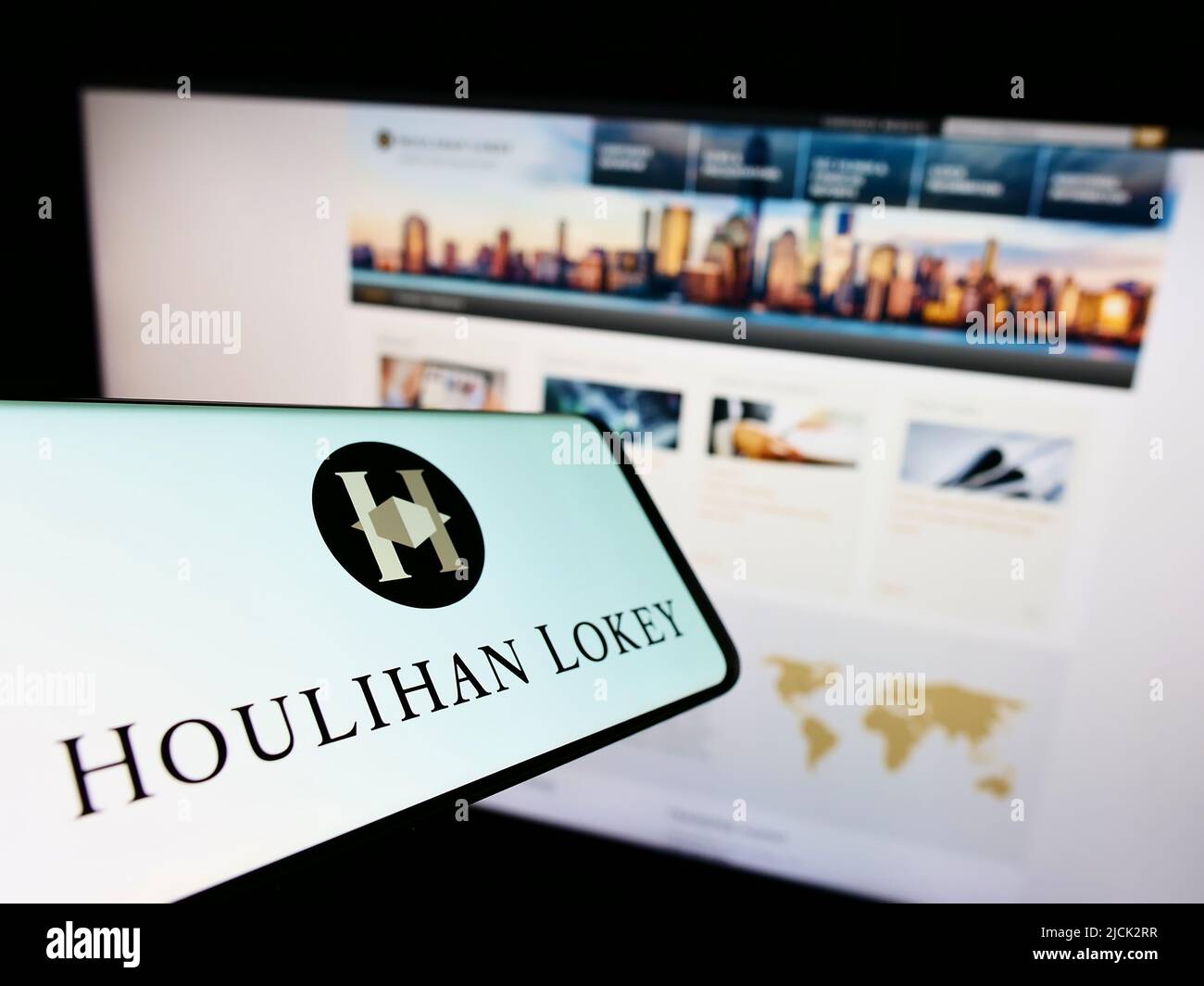 Téléphone portable avec logo de la société d'investissement américaine Houlihan Lokey Inc. À l'écran devant le site Web des affaires. Effectuez la mise au point au centre-droit de l'écran du téléphone. Banque D'Images