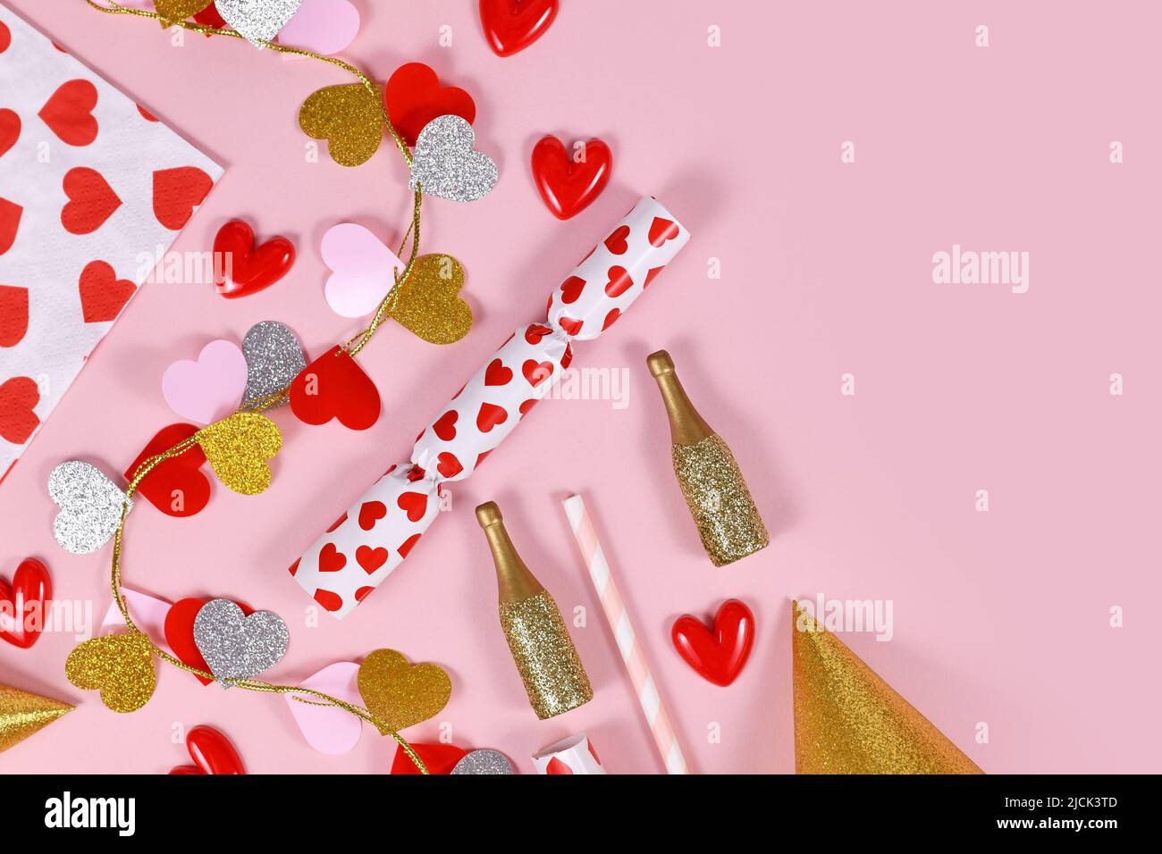 Plat de fête avec guirlande en forme de coeur, serviette, bouteilles de champagne et chapeaux de fête sur fond rose Banque D'Images Plat de fête avec guirlande en forme de coeur, serviette, bouteilles de champagne et chapeaux de fête sur fond rose Banque D'Images