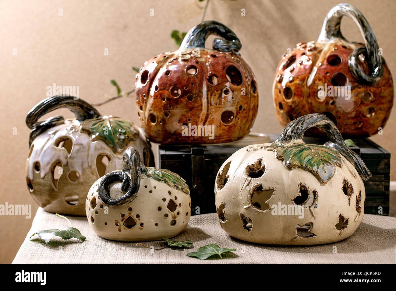 Décorations d'Halloween, ensemble de citrouilles en céramique sculptées blanches et brunes sur une table avec des feuilles de lierre. Fête d'Halloween ou de Thanksgiving Banque D'Images