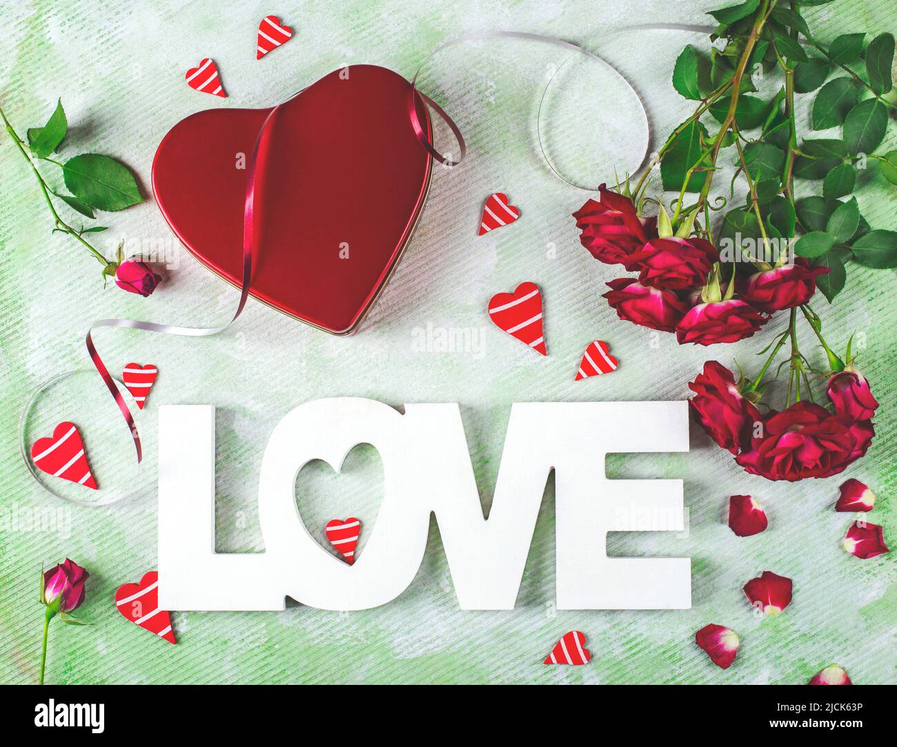 Composition festive de l'amour pour la Saint-Valentin faite avec boîte cadeau rouge et roses, coeurs et mot Amour. Pose à plat. Banque D'Images
