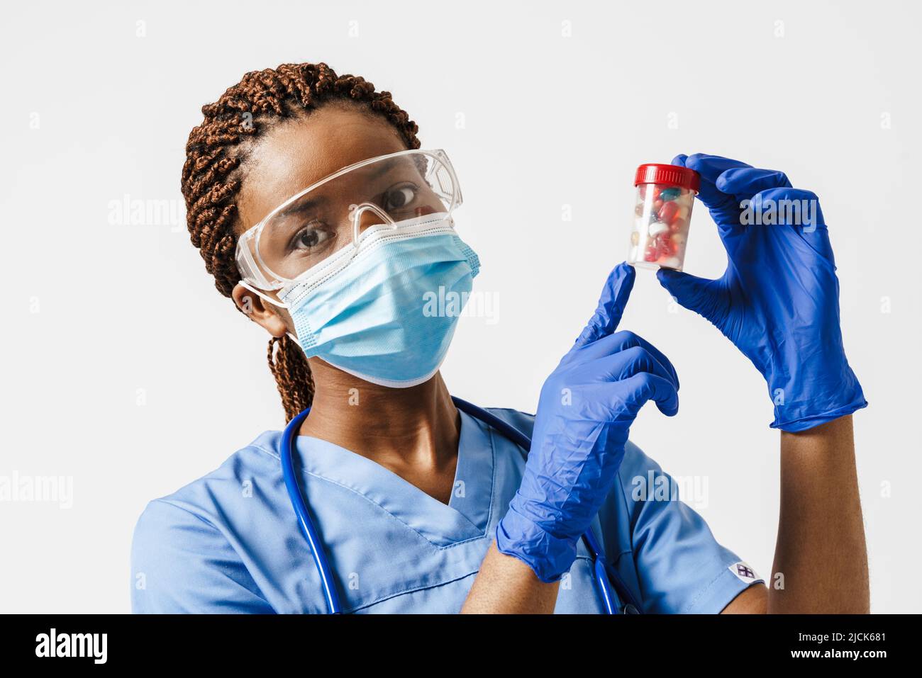 Médecin enceinte noire portant un masque facial montrant des pilules isolées sur fond blanc Banque D'Images