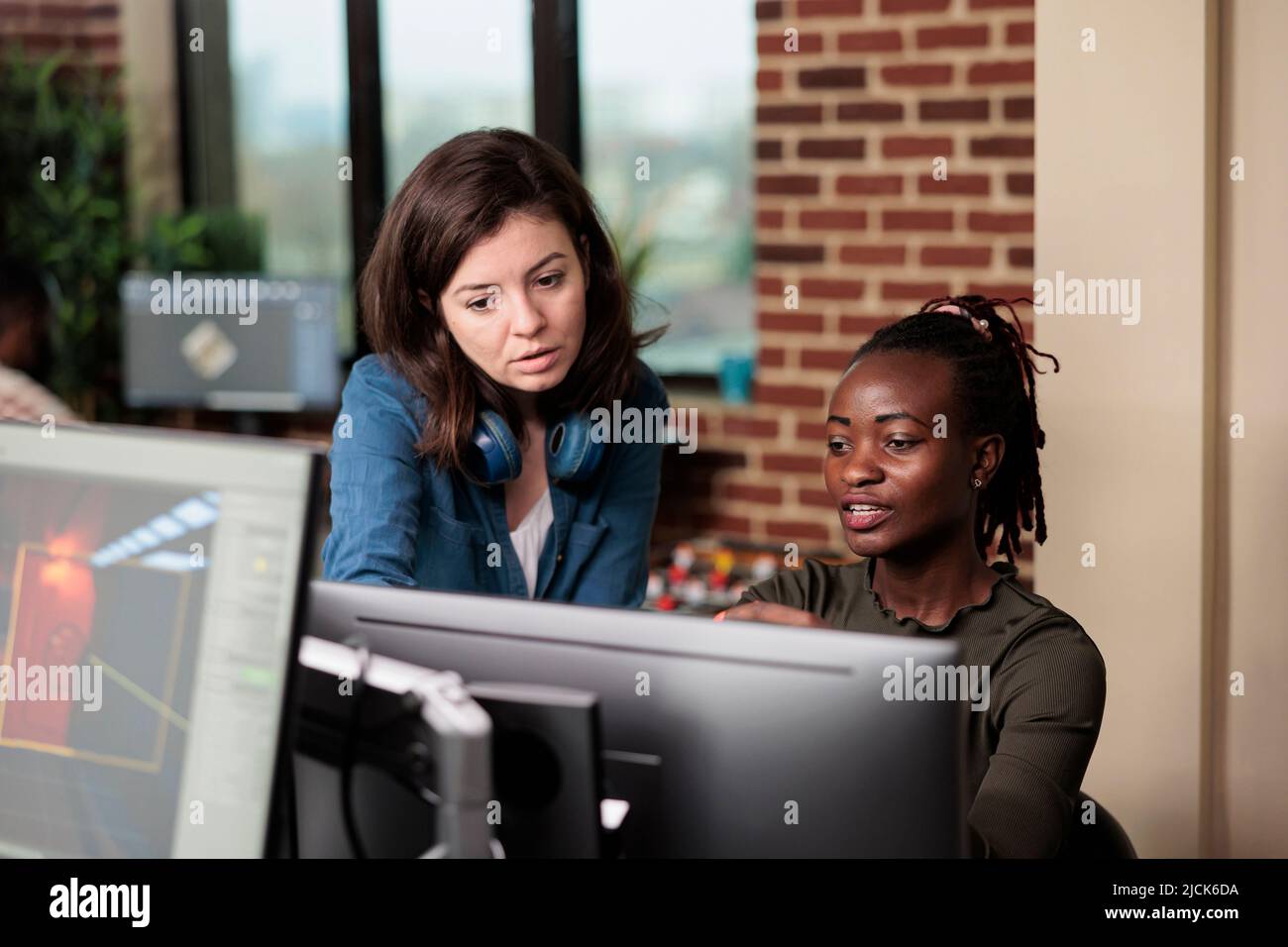 Collègues multiethniques dans la conversation sur la technologie de développement graphique et comment l'améliorer. Artiste numérique afro-américain discutant avec le chef d'équipe de logiciels de conception défectueux. Banque D'Images