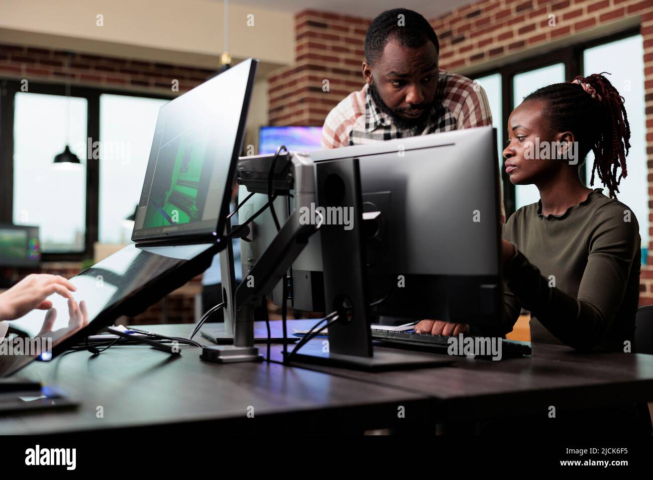 Des employés de bureau américains africains créatifs discutant des progrès réalisés dans le développement de 3D projets. Divers collègues discutant de l'art numérique professionnel tout en étant assis au bureau dans l'espace de travail. Banque D'Images