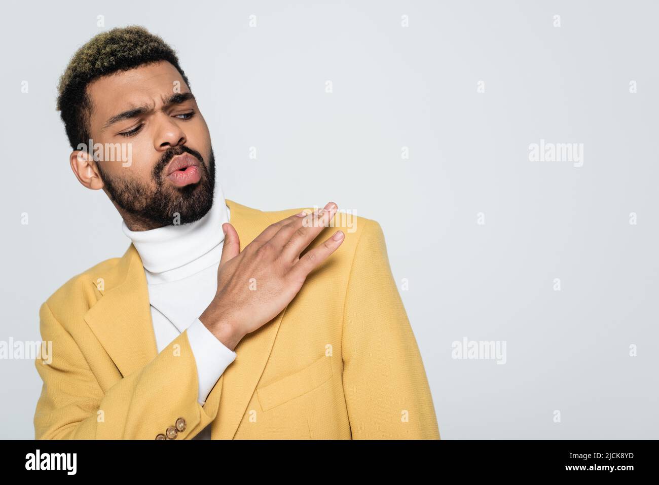 jeune afro-américain en blazer jaune et col polo poussière de l'épaule isolée sur gris Banque D'Images