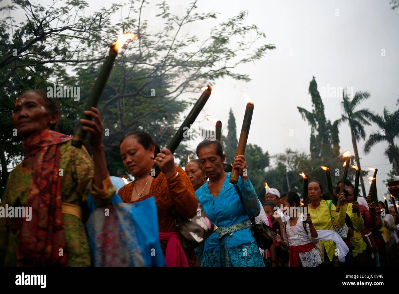 Femme plus âgée portant une torche traditionnelle pour une série d'événements célébrant le jour de Nyepi à Kediri, Eastjava, Indonésie Banque D'Images