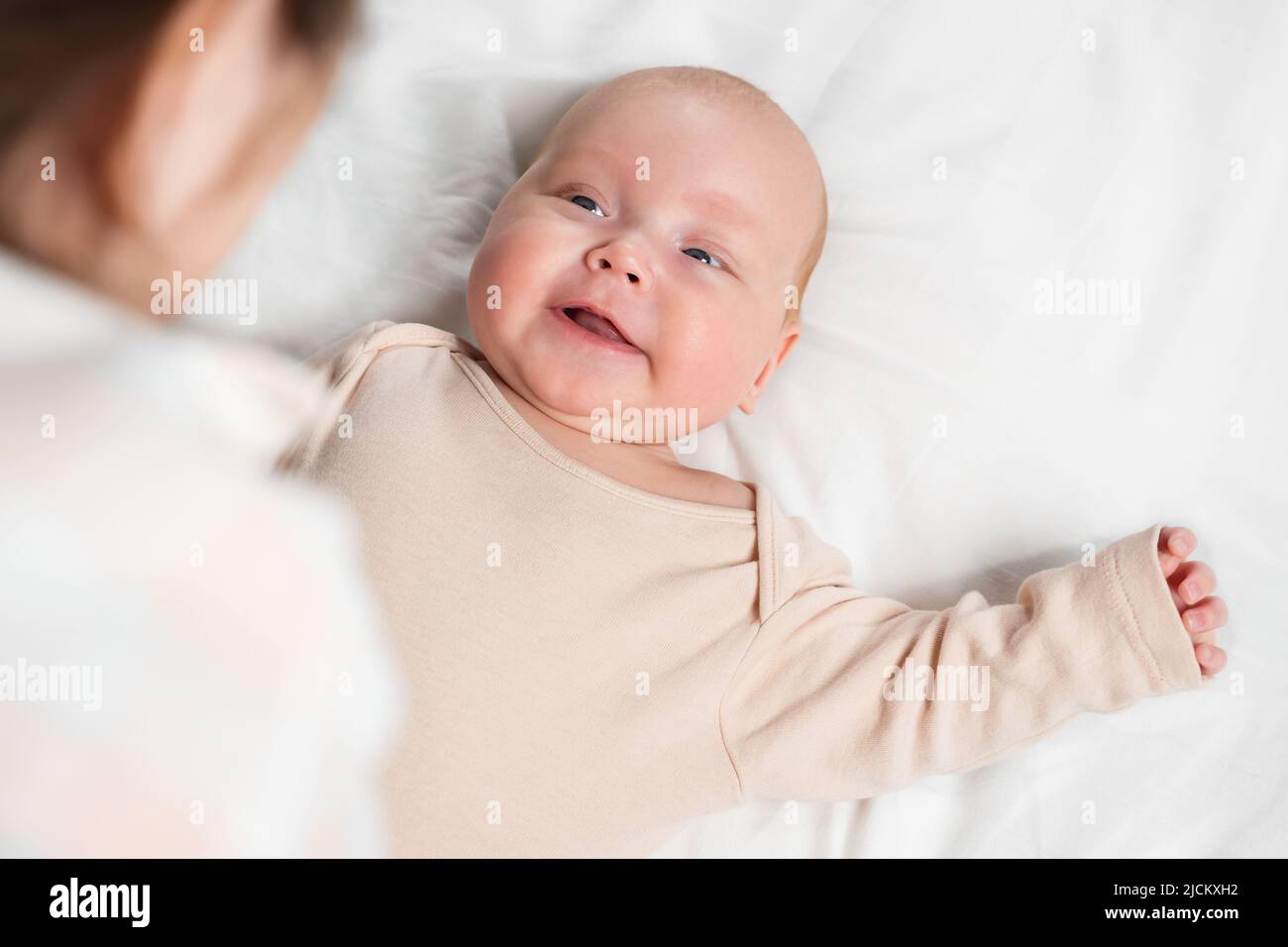 Mère parle à petite fille douce couché sur le lit à la maison Banque D'Images