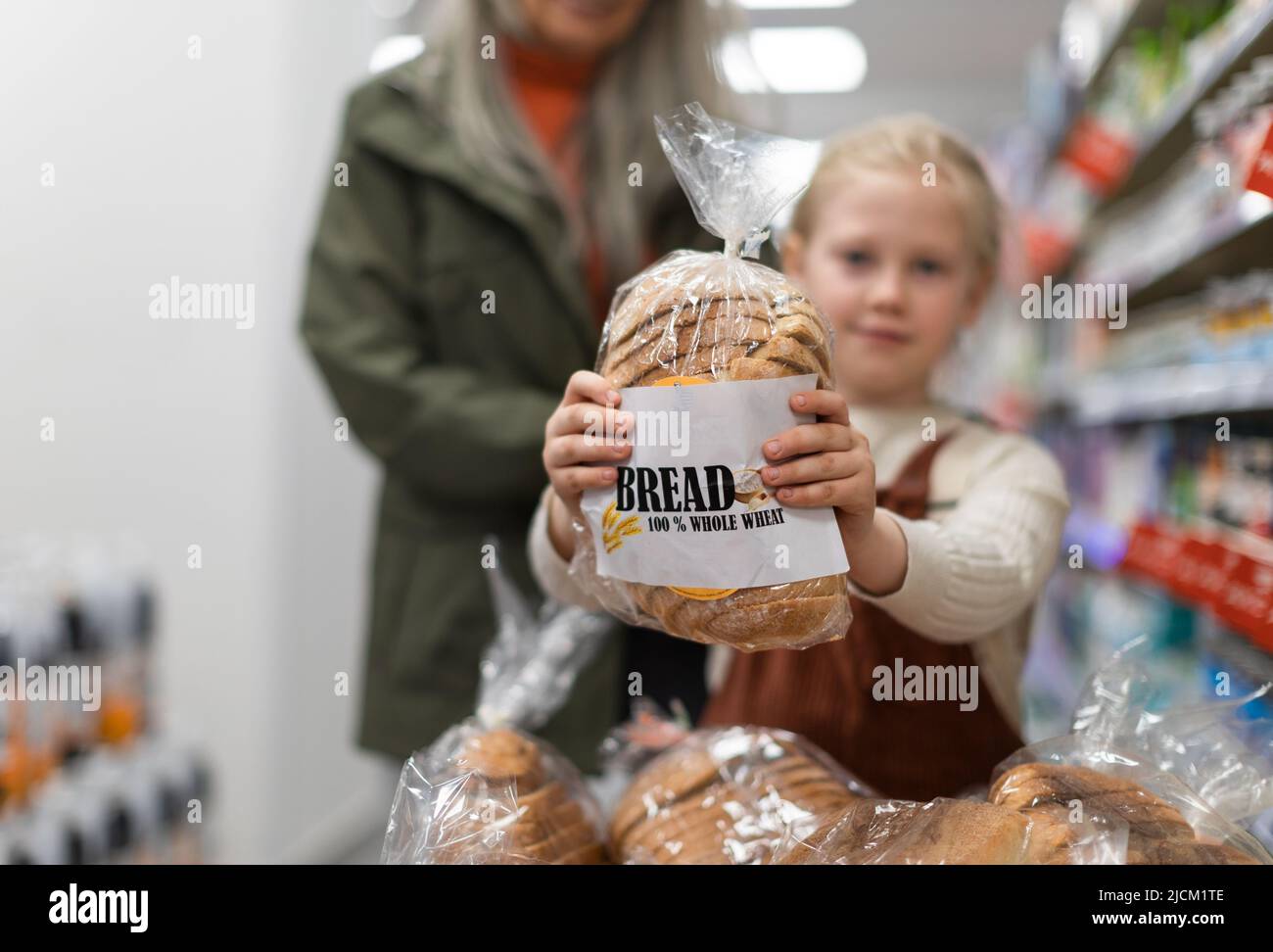 Petite fille assise dans le chariot pendant les achats en famille dans l'hypermarché Banque D'Images