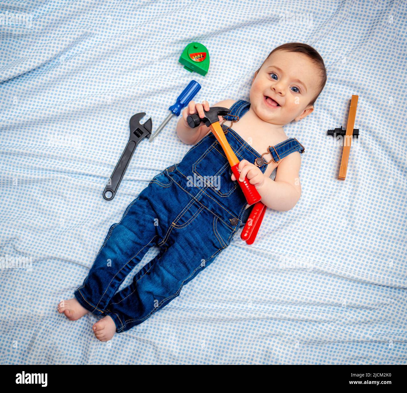 bébé garçon de 6 mois vêtu d'une combinaison en denim tout en jouant à  l'ouvrier de l'outillage. Il ressemble à un petit menuisier ou un petit  plombier Photo Stock - Alamy