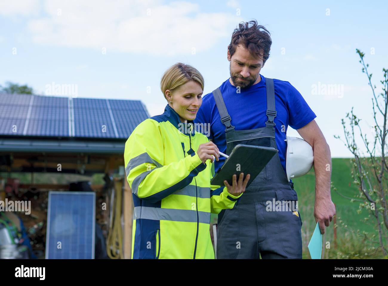 Homme et femme installateurs solaires ingénieurs avec la tablette tout en installant le système de panneau solaire à la maison. Banque D'Images