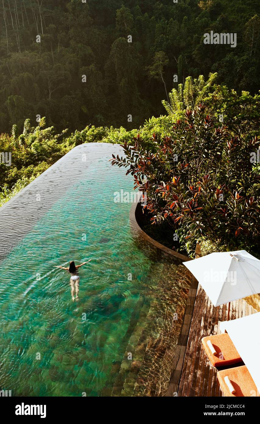 Femme nageant dans la piscine à débordement, Ubud Hanging Gardens, Bali, Indonésie. La piscine à débordement fait face à la vallée de la rivière Ayung. Banque D'Images