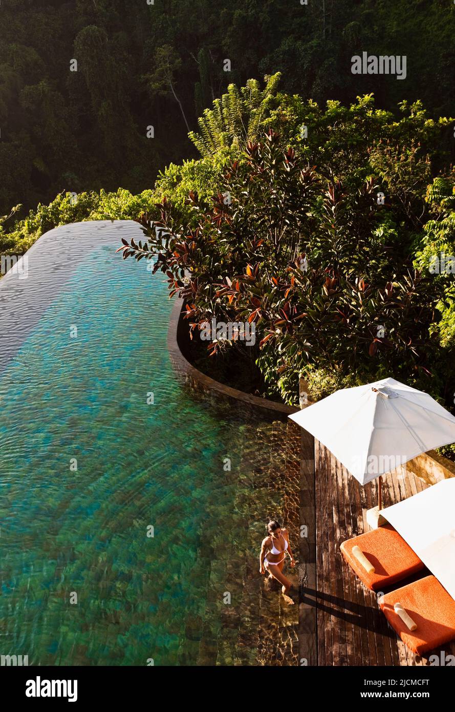 Femme sortant de la piscine à débordement principale, Ubud Hanging Gardens, Bali, Indonésie. La piscine à débordement principale fait face à la vallée de la rivière Ayung. Banque D'Images