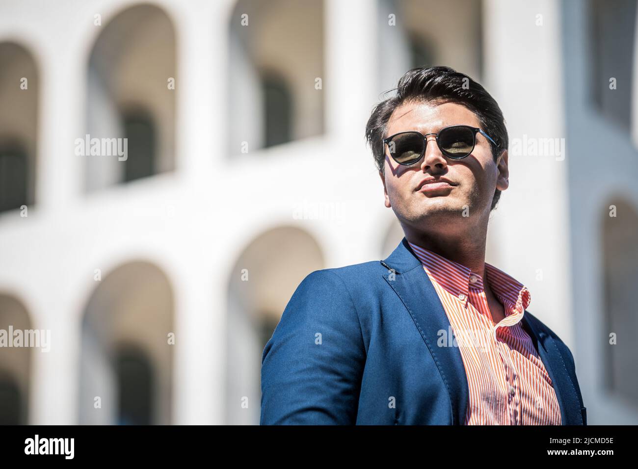 Homme d'affaires avec lunettes de soleil. Veste et chemise bleu. En arrière-plan un bâtiment. Banque D'Images