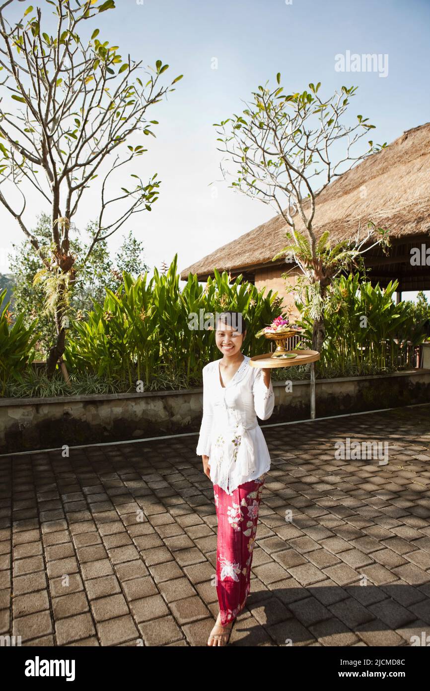 Femme balinaise faisant des offrandes le matin aux jardins suspendus d'Ubud, Bali, Indonésie. Les balinais font des plats du matin aux spiritueux sur une base quotidienne. Banque D'Images