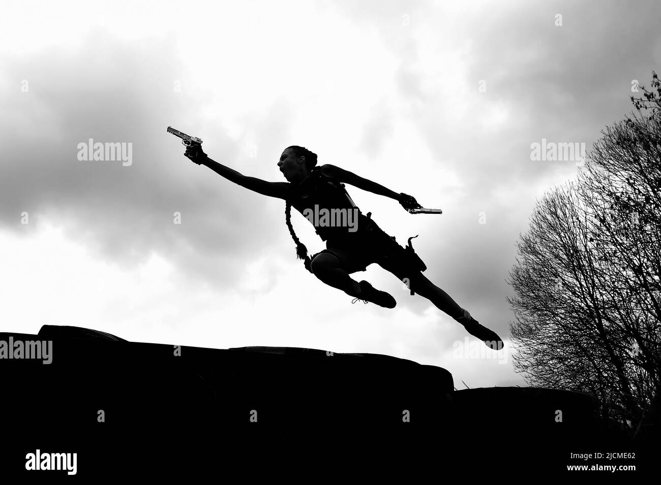 Une jeune femme se pose comme une silhouette de son super-héros d'action cosplay Lara Croft. Banque D'Images