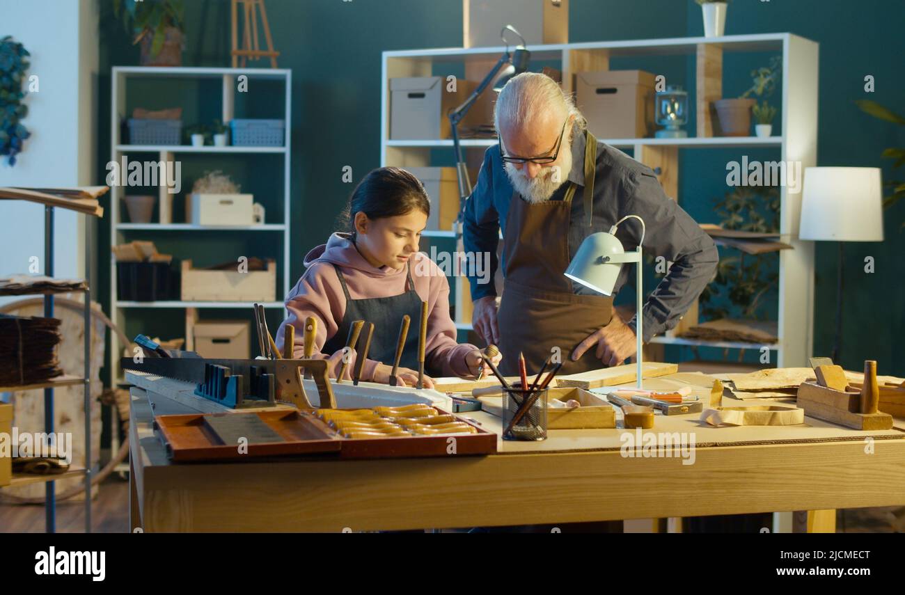 Grand-père attentionné avec sa petite-fille adolescente passer du temps ensemble, travailler sur le bois, profiter de la communication dans l'atelier. Garage passe-temps. Communicati Banque D'Images