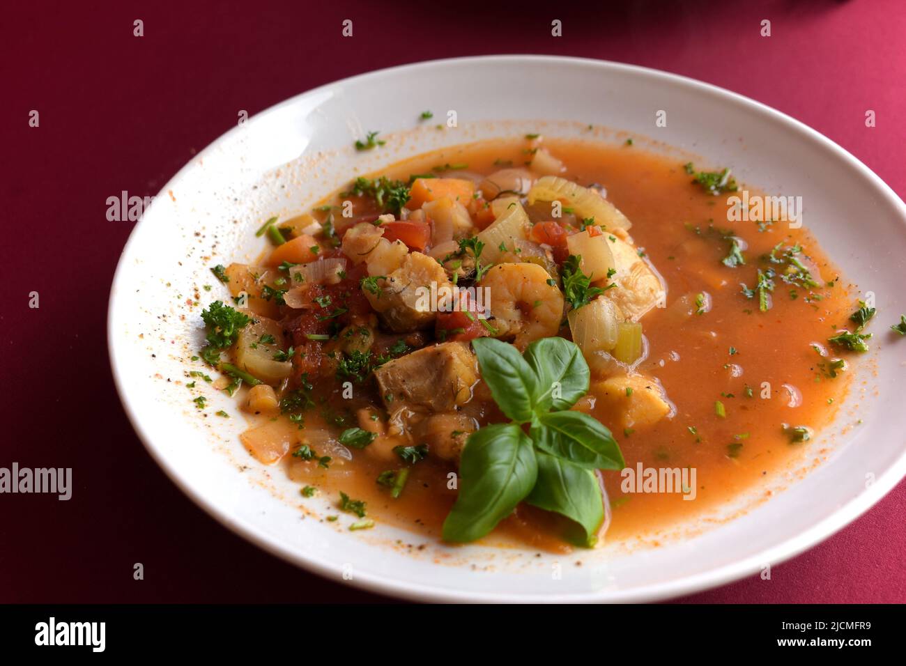 Savoureuse bouillabaisse, fruits de mer et soupe de poisson, servie sur une assiette blanche, avec une décoration au basilic Banque D'Images