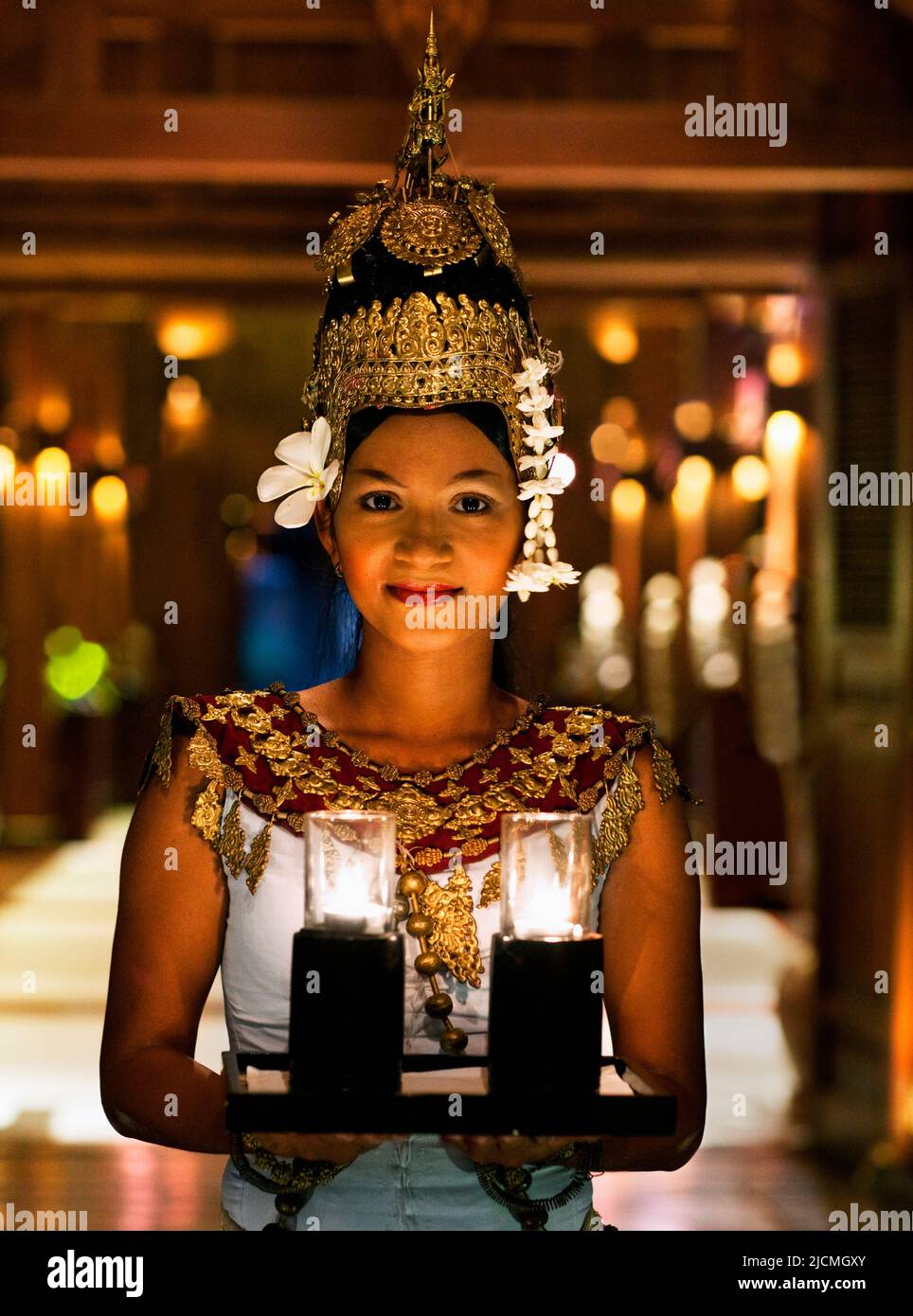 Une jeune danseuse cambodgienne Apsara accueille ses invités avec un plateau de bougies au crépuscule à l'entrée d'un hôtel, Siem Reap, Cambodge. Banque D'Images