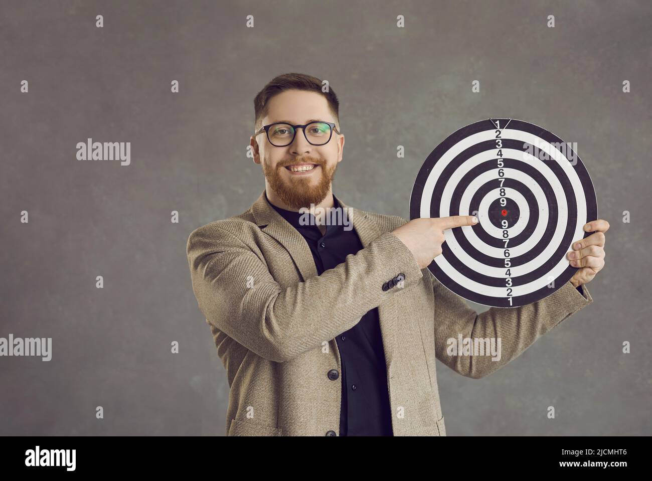 Un jeune homme heureux qui se tourne vers la cible comme métaphore pour fixer un objectif d'affaires Banque D'Images