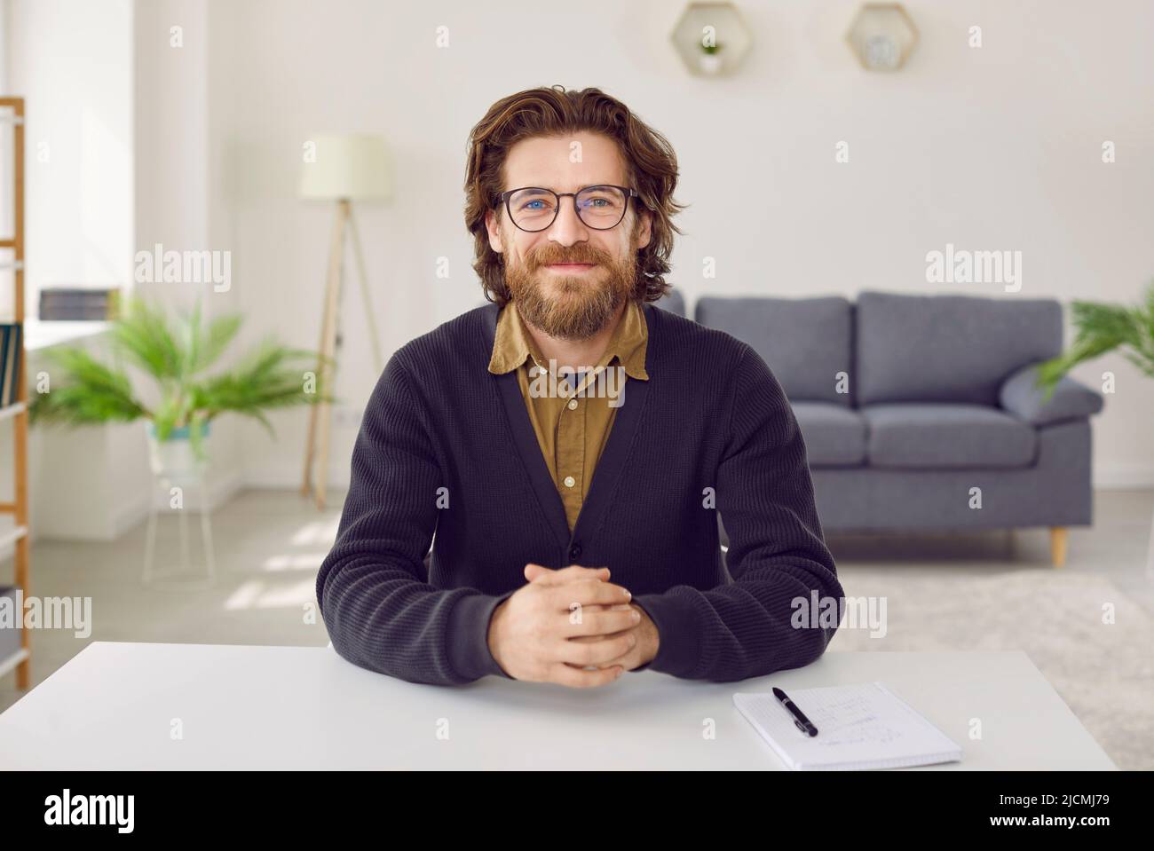 Portrait d'un homme d'affaires heureux ou d'un enseignant assis à un bureau pendant une conférence en ligne Banque D'Images