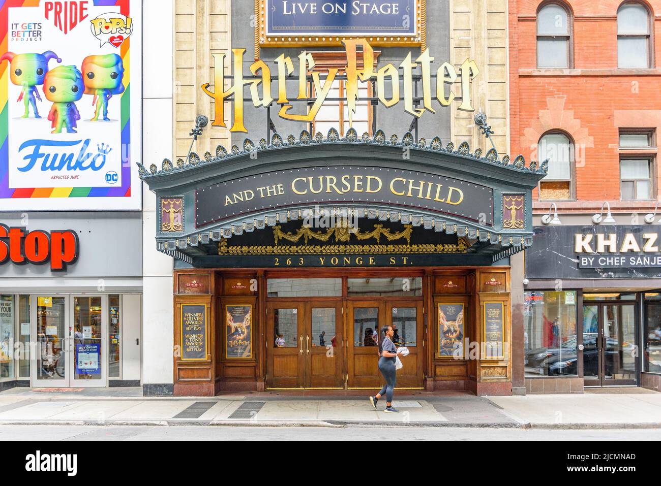 Une femme marche à côté d'un signe de la pièce Harry Potter et l'enfant maudit. L'image montre l'entrée du théâtre Ed Mirvish situé dans la rue Yonge Banque D'Images