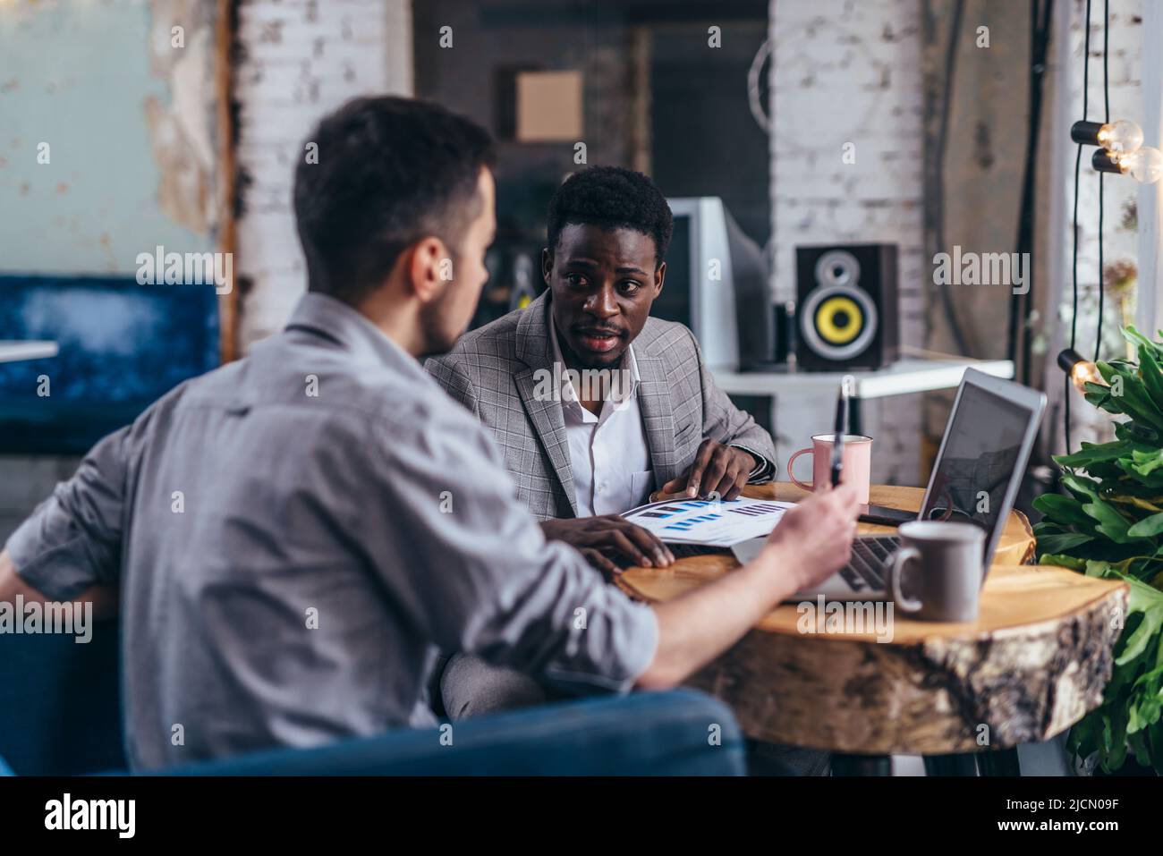 Partenaires d'affaires dans une réunion avec un jeune homme utilisant un ordinateur portable et homme afro-américain Banque D'Images