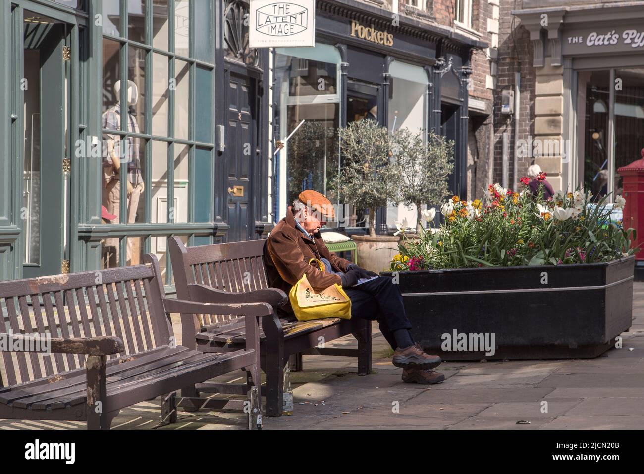 Un homme d'âge moyen portant une casquette écrit dans un livre tout en  étant assis sur un banc dans la rue Photo Stock - Alamy