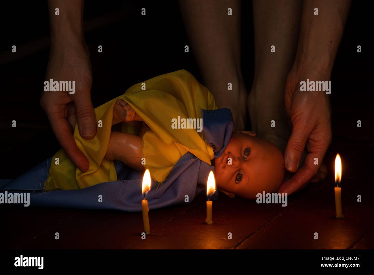 Une poupée d'enfants avec le drapeau de l'Ukraine se trouve sur le sol de la maison dans l'obscurité et à côté des jambes de la fille, la guerre en Ukraine, la mort de ch Banque D'Images