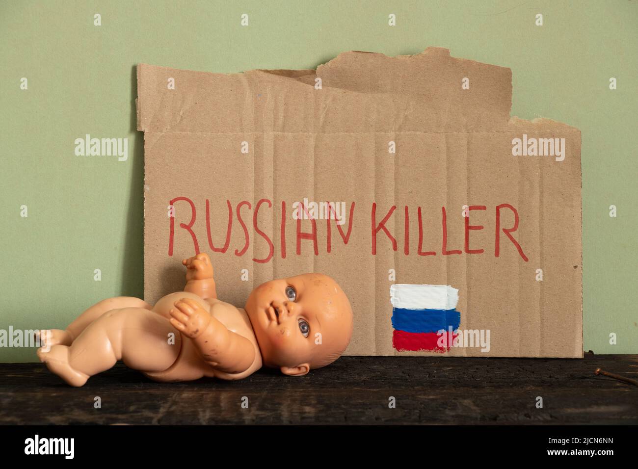 Un panneau avec le texte russe tueur et le drapeau de la Russie à côté de lui se trouve une poupée d'enfants sur le sol, la mort d'enfants pendant la guerre à UKR Banque D'Images
