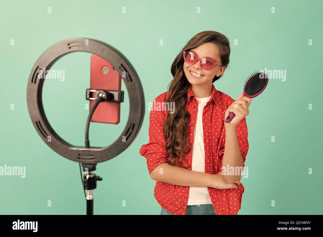 enfant beauté blogger. soins des cheveux. enfant dans les lunettes de soleil prendre soin des cheveux. vlogger tenir la brosse à cheveux. Banque D'Images