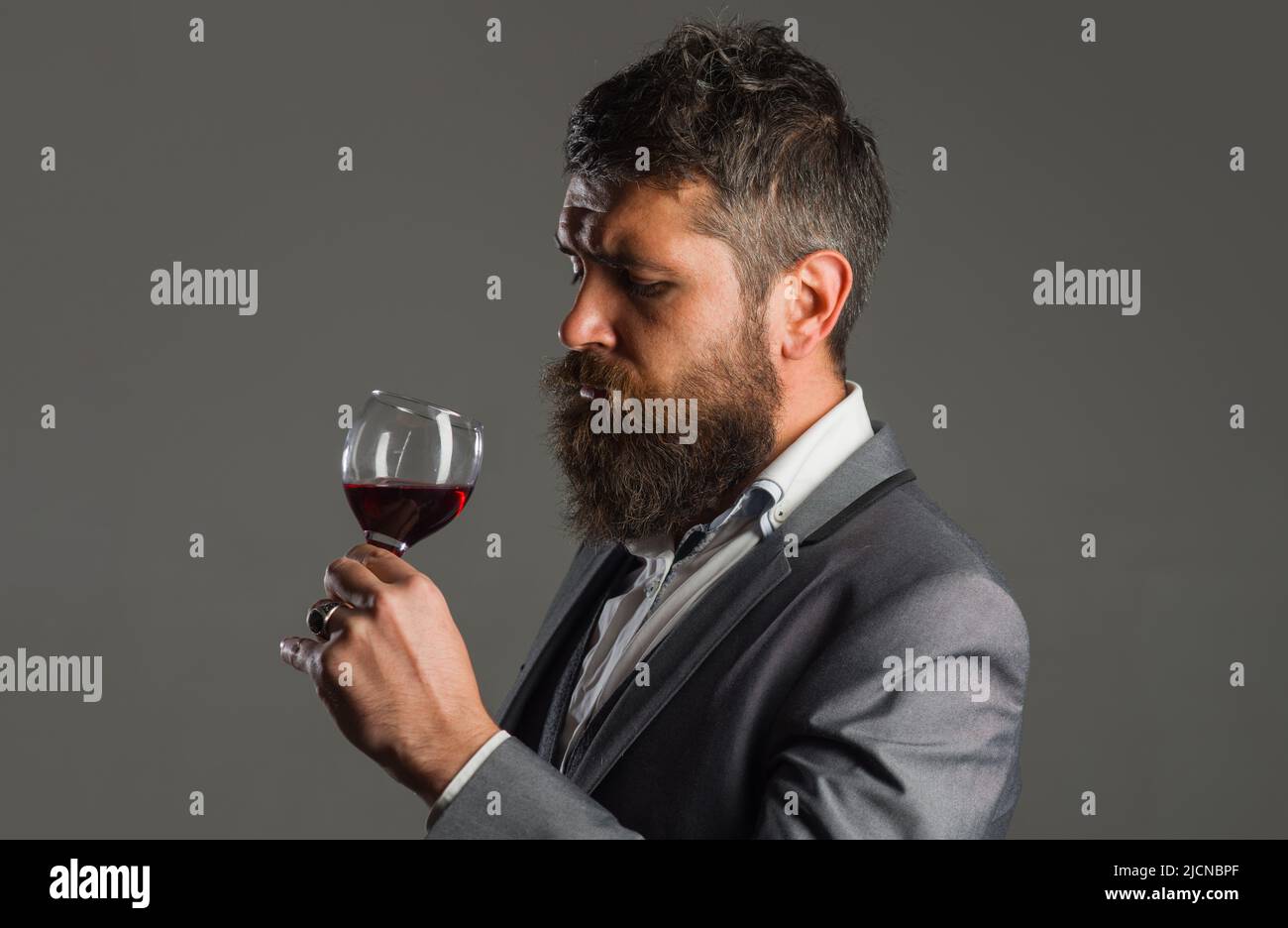 Homme barbu qui boit du vin rouge. Dégustation d'alcool. Un gars sympa avec de l'alcool. Sommelier à lunettes de vin. Banque D'Images